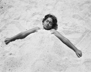 A black and white photo of a young boy laying in the sand Mimi Plumb The Reservoir